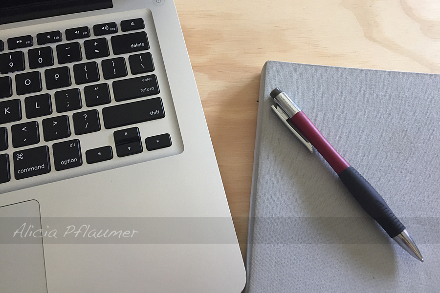 A laptop keyboard, hardcover notebook, and a pencil.